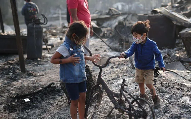 Dos niños junto a una bicicleta dañada por el fuego, entre las cenizas que dejaron los incendios del sur de Oregón
