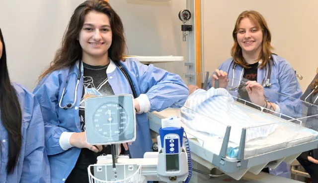 Cuatro estudiantes de Career Build con uniforme médico practicando cuidado de pacientes en un laboratorio de capacitación en salud